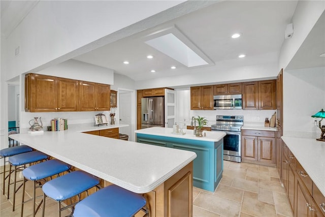 2410 47th Ter, Vero Beach, FL 32966 - kitchen with stainless steel appliances, a breakfast bar, a center island, brown cabinetry, and light countertops