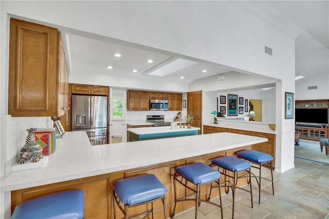 2410 47th Ter, Vero Beach, FL 32966 - kitchen with stainless steel appliances, a peninsula, light countertops, brown cabinets, and recessed lighting