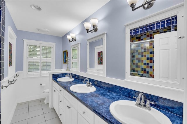 2410 47th Ter, Vero Beach, FL 32966 - full bath featuring tile patterned flooring, double vanity, a wainscoted wall, and a shower
