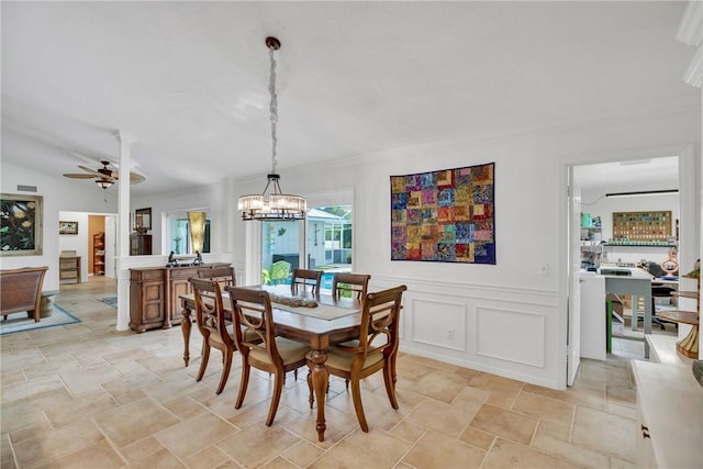 2410 47th Ter, Vero Beach, FL 32966 - dining area with a chandelier, light stone finish floors, a ceiling fan, wainscoting, and a decorative wall