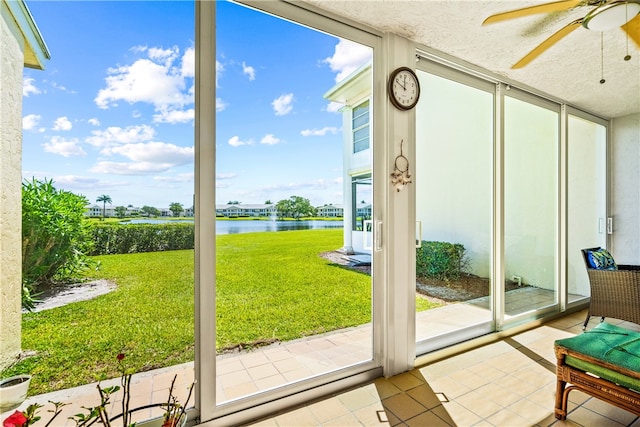 doorway to outside featuring a water view, expansive windows, tile patterned flooring, and ceiling fan