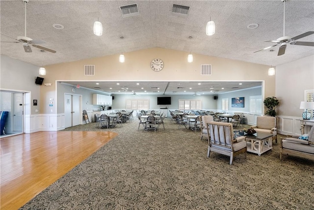 interior space featuring ceiling fan, a textured ceiling, hardwood / wood-style flooring, and vaulted ceiling