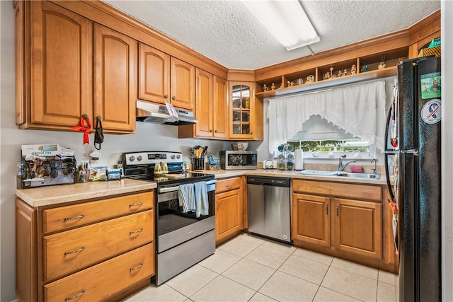 kitchen with light tile patterned floors, sink, stainless steel appliances, and a textured ceiling