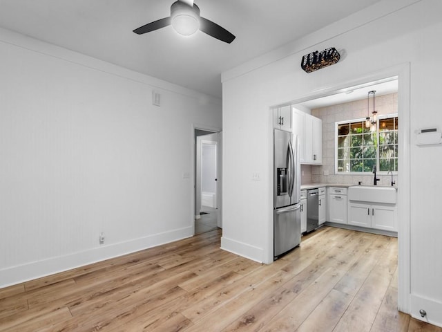 kitchen featuring white cabinetry, appliances with stainless steel finishes, decorative backsplash, light wood-type flooring, and sink