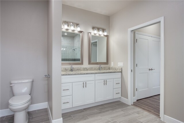 bathroom with vanity, toilet, and tiled shower