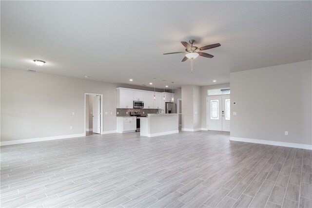 unfurnished living room featuring french doors, light wood-type flooring, and ceiling fan