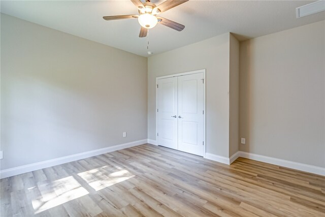 unfurnished bedroom featuring ceiling fan, a closet, and light hardwood / wood-style flooring