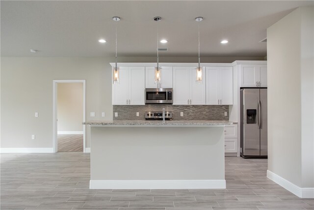 kitchen featuring stainless steel appliances, light stone counters, light hardwood / wood-style flooring, white cabinets, and pendant lighting