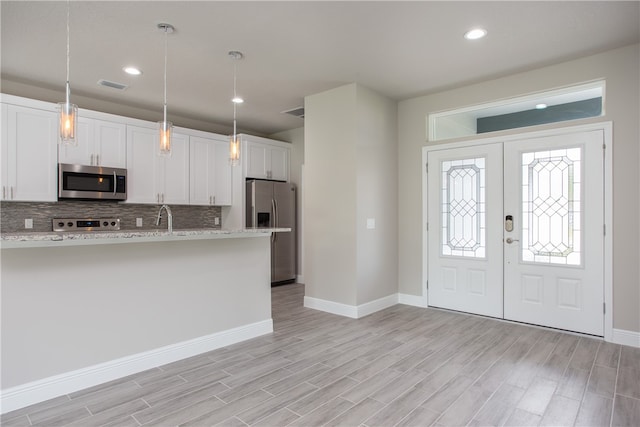 kitchen featuring stainless steel appliances, white cabinets, and light wood-type flooring