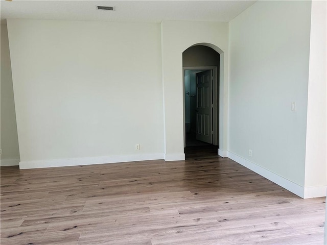 6075 46th Ln, Vero Beach, FL 32967 - empty room with arched walkways, wood finished floors, and baseboards