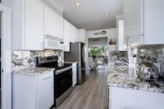 8720 Wakefield Dr, West Palm Beach, FL 33410 - kitchen featuring tasteful backsplash, stainless steel electric range, white microwave, light wood-style flooring, and white cabinets