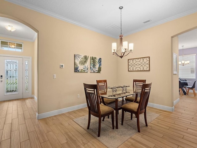 dining area featuring ornamental molding, light wood-type flooring, and a notable chandelier