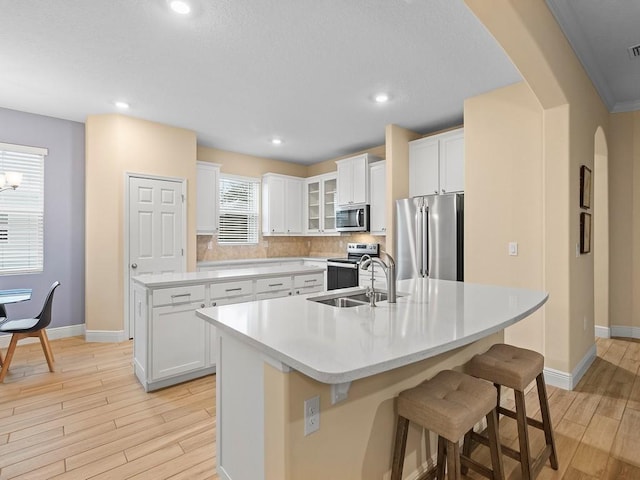 kitchen featuring white cabinetry, stainless steel appliances, and an island with sink