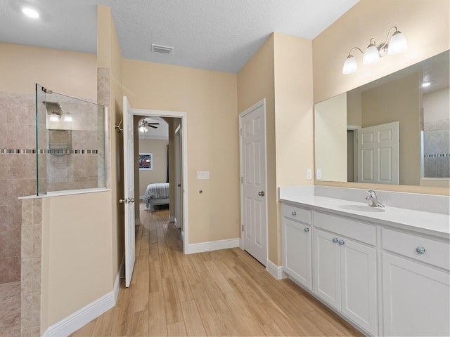 bathroom with a tile shower, vanity, hardwood / wood-style flooring, and a textured ceiling