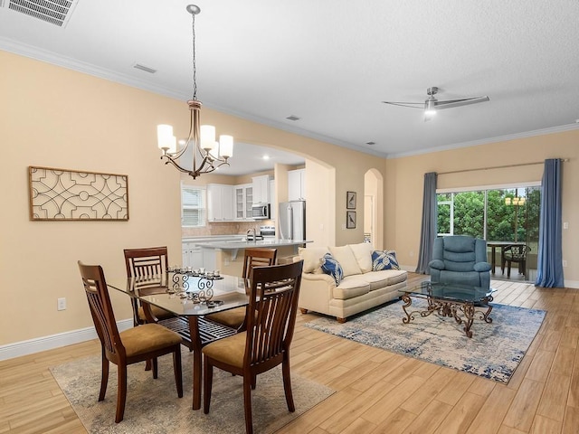 dining room featuring crown molding, ceiling fan with notable chandelier, and light wood-type flooring