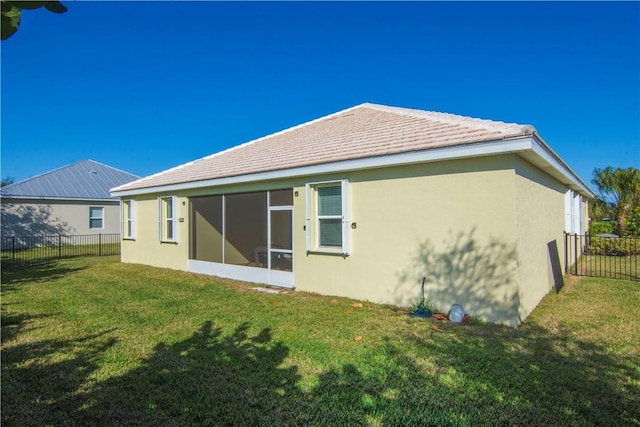 rear view of house featuring a lawn and a sunroom