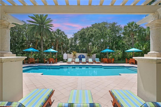 pool at dusk featuring a patio