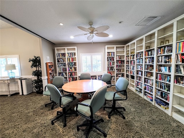 carpeted home office with a textured ceiling and ceiling fan