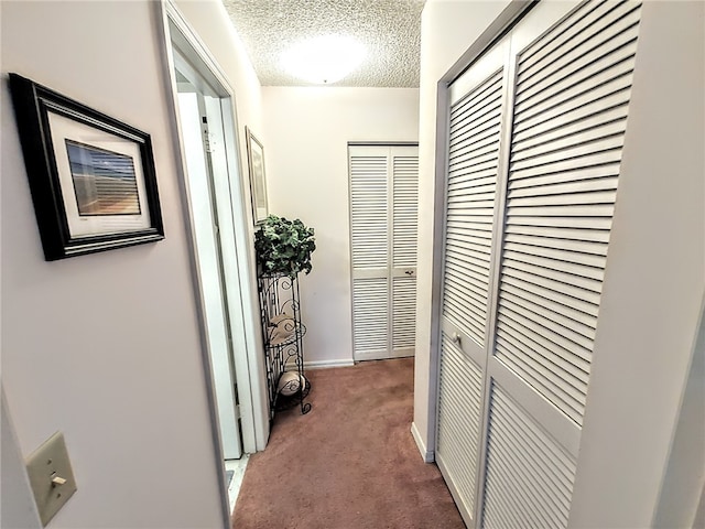 hallway featuring carpet and a textured ceiling