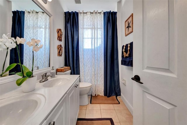 bathroom featuring tile patterned flooring, double vanity, toilet, and a sink