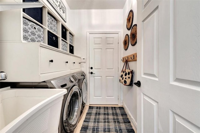 washroom with cabinet space, washing machine and dryer, and a sink