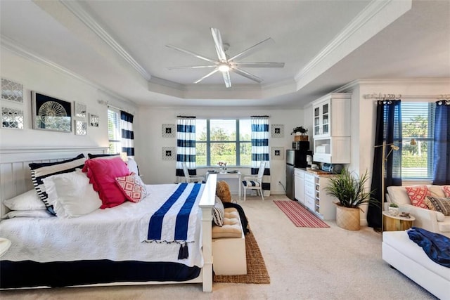 bedroom with a tray ceiling, light colored carpet, ornamental molding, and a ceiling fan