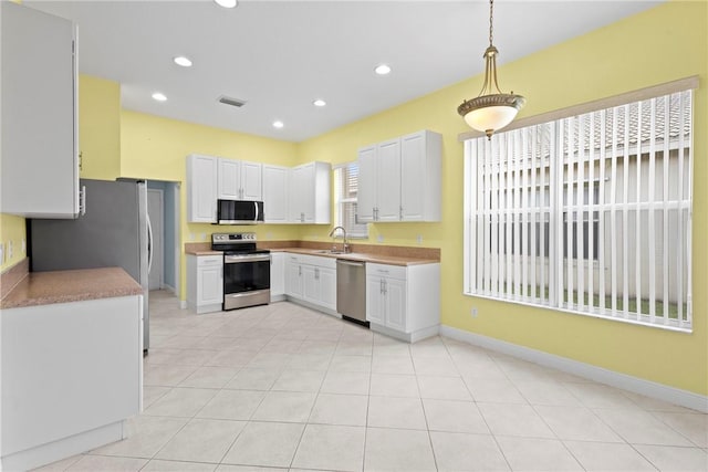 1877 Grey Falcon Cir SW, Vero Beach, FL 32962 - kitchen with stainless steel appliances, baseboards, recessed lighting, hanging light fixtures, and white cabinets