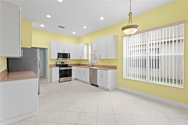 1877 Grey Falcon Cir SW, Vero Beach, FL 32962 - kitchen with stainless steel appliances, baseboards, recessed lighting, hanging light fixtures, and white cabinets