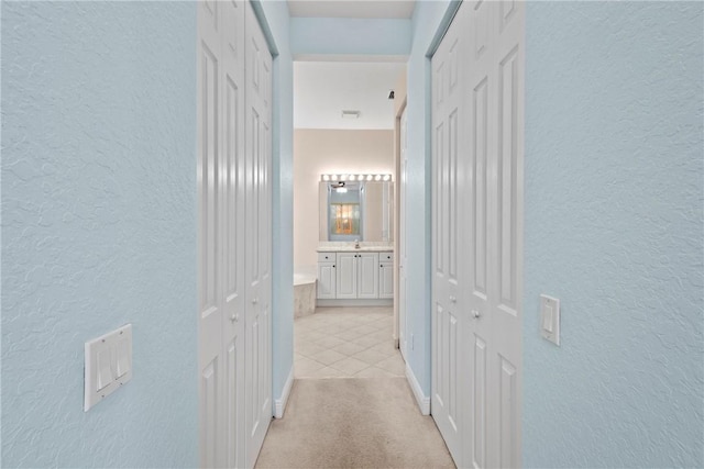 1877 Grey Falcon Cir SW, Vero Beach, FL 32962 - hallway with a textured wall, light tile patterned flooring, baseboards, and light carpet