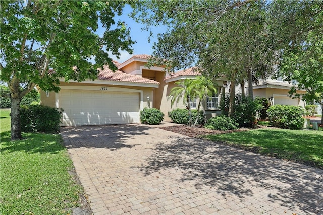 1877 Grey Falcon Cir SW, Vero Beach, FL 32962 - mediterranean / spanish home with stucco siding, a front lawn, an attached garage, and decorative driveway