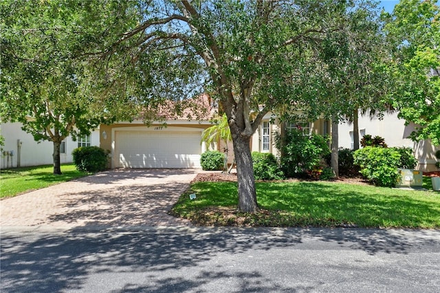 1877 Grey Falcon Cir SW, Vero Beach, FL 32962 - obstructed view of property with stucco siding, driveway, a garage, and a front lawn
