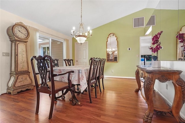 dining room featuring hardwood / wood-style flooring, vaulted ceiling, and a notable chandelier