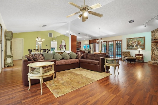 living room with ceiling fan with notable chandelier, dark hardwood / wood-style flooring, vaulted ceiling, and a textured ceiling