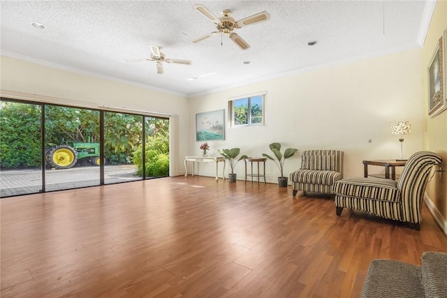 sitting room with hardwood / wood-style flooring, ceiling fan, crown molding, and a textured ceiling