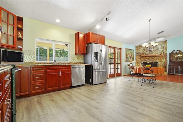 kitchen featuring decorative light fixtures, light hardwood / wood-style floors, stainless steel appliances, light stone countertops, and a healthy amount of sunlight