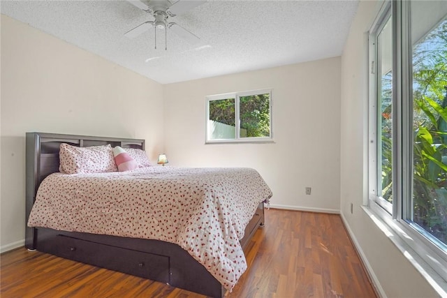 bedroom with ceiling fan, dark hardwood / wood-style floors, and a textured ceiling