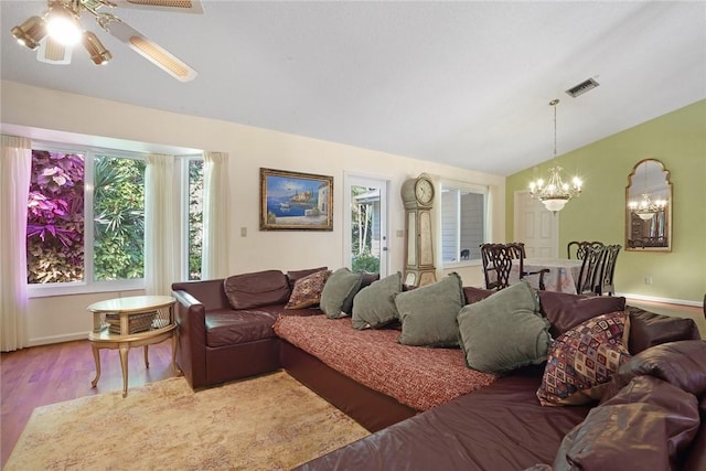 living room featuring ceiling fan with notable chandelier, vaulted ceiling, and hardwood / wood-style floors