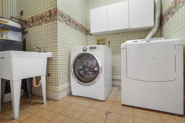 laundry area featuring light tile patterned floors, cabinets, and washing machine and clothes dryer