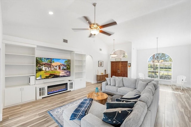 living room featuring ceiling fan with notable chandelier and light hardwood / wood-style floors