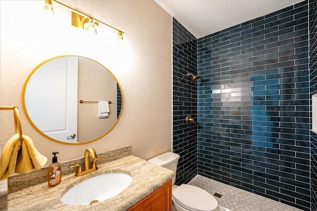 bathroom with tiled shower, vanity, and toilet