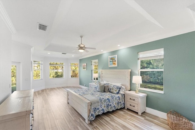 bedroom featuring multiple windows, a raised ceiling, ceiling fan, and light hardwood / wood-style flooring