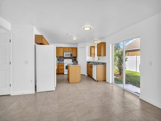 5985 Ridge Lake Cir, Vero Beach, FL 32967 - kitchen with white appliances, a center island, tasteful backsplash, and brown cabinetry
