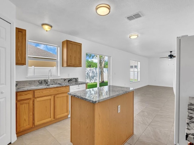 5985 Ridge Lake Cir, Vero Beach, FL 32967 - kitchen featuring freestanding refrigerator, a kitchen island, stone counters, ceiling fan, and open floor plan
