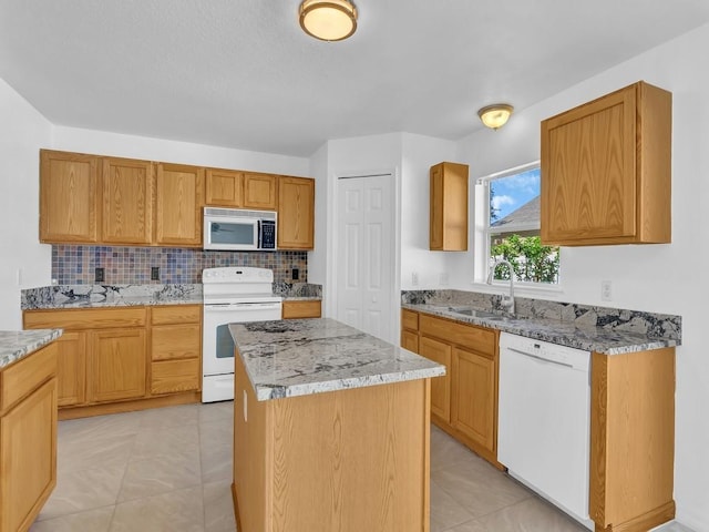 5985 Ridge Lake Cir, Vero Beach, FL 32967 - kitchen featuring white appliances, light stone countertops, a center island, tasteful backsplash, and light tile patterned floors