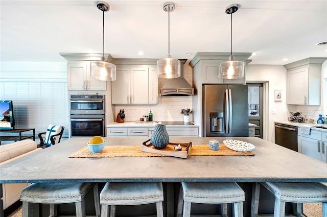 kitchen featuring a kitchen breakfast bar, hanging light fixtures, a kitchen island, custom range hood, and stainless steel appliances