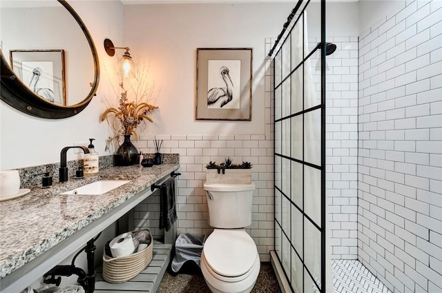 bathroom featuring a tile shower, vanity, toilet, and tile walls