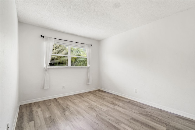 spare room with light hardwood / wood-style flooring and a textured ceiling