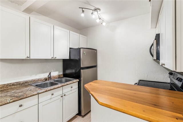 kitchen with dark stone countertops, appliances with stainless steel finishes, sink, and white cabinets