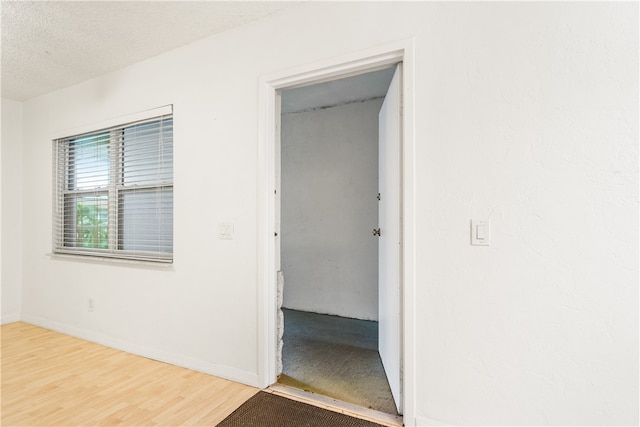 hall with hardwood / wood-style floors and a textured ceiling