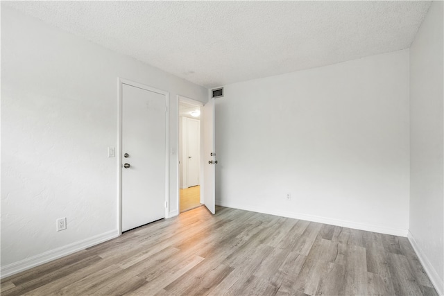 empty room featuring light hardwood / wood-style flooring and a textured ceiling